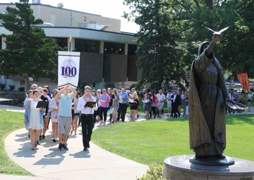 The Avila community marches across campus together in a long line promoting peace.